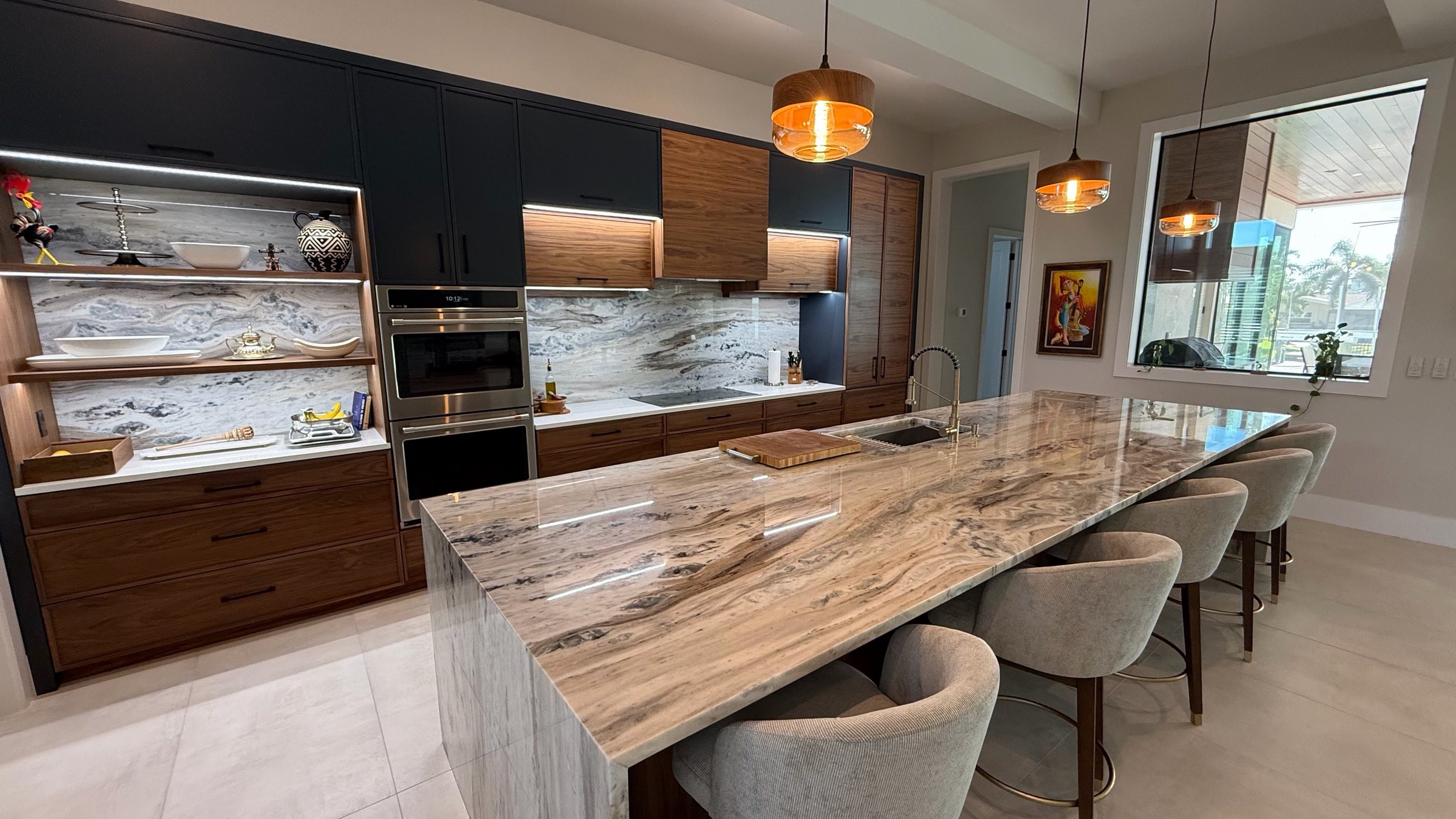 Long waterfall island and bookmatched stone backsplash in an HB kitchen